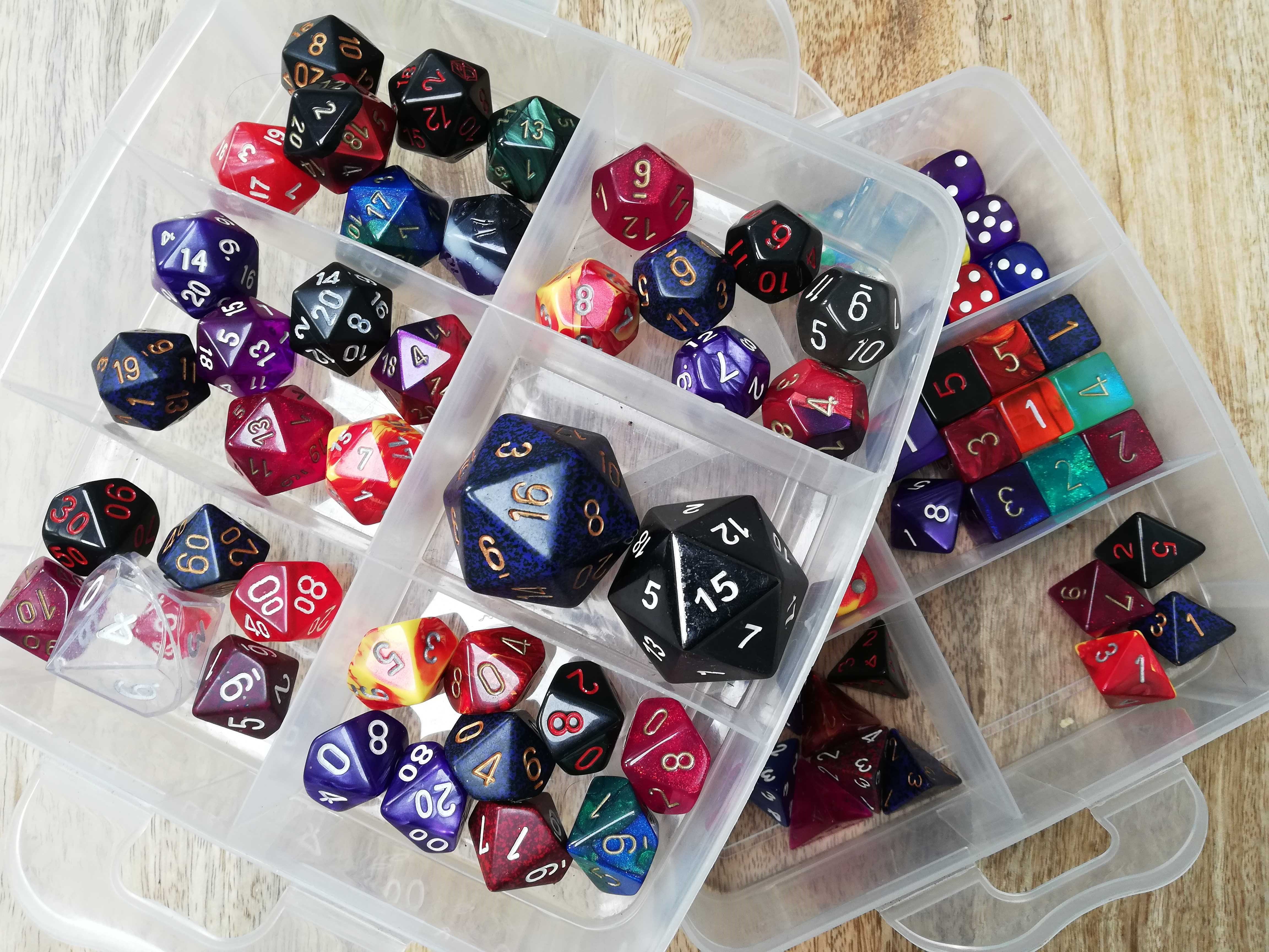 Photo of two plastic organising boxes full of dice of various shapes and colours, from large 20-sided dice to 4-sided dice